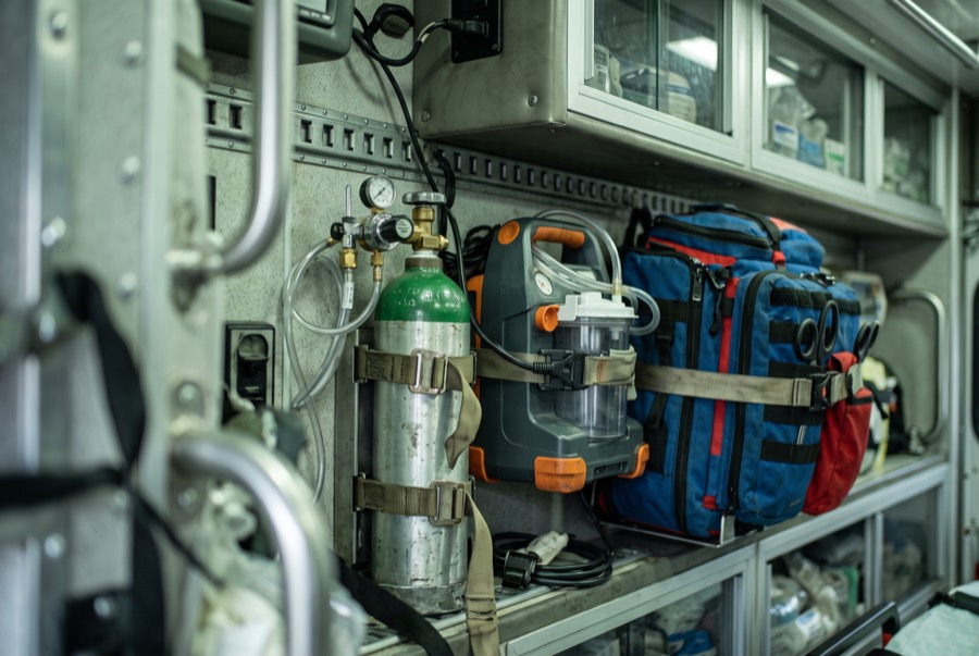 Portable oxygen cylinder, suction unit, and airway bag mounted in an ambulance compartment